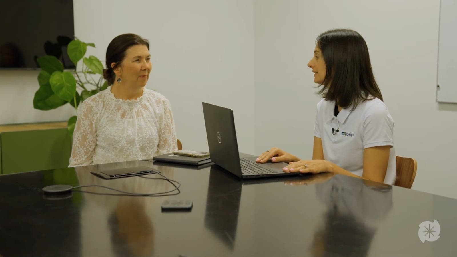 An immigration adviser at a meeting table with a laptop, talking with a client